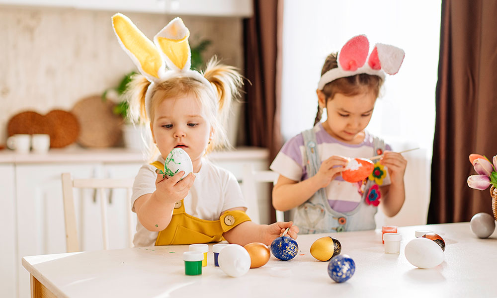 Easter-holiday Two small girls in a kitchen eating Easter eggs
