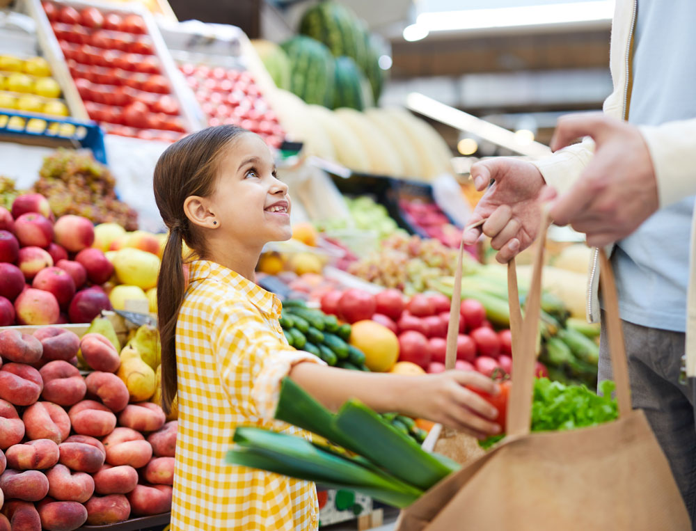 A girl buying some vegetables at a market