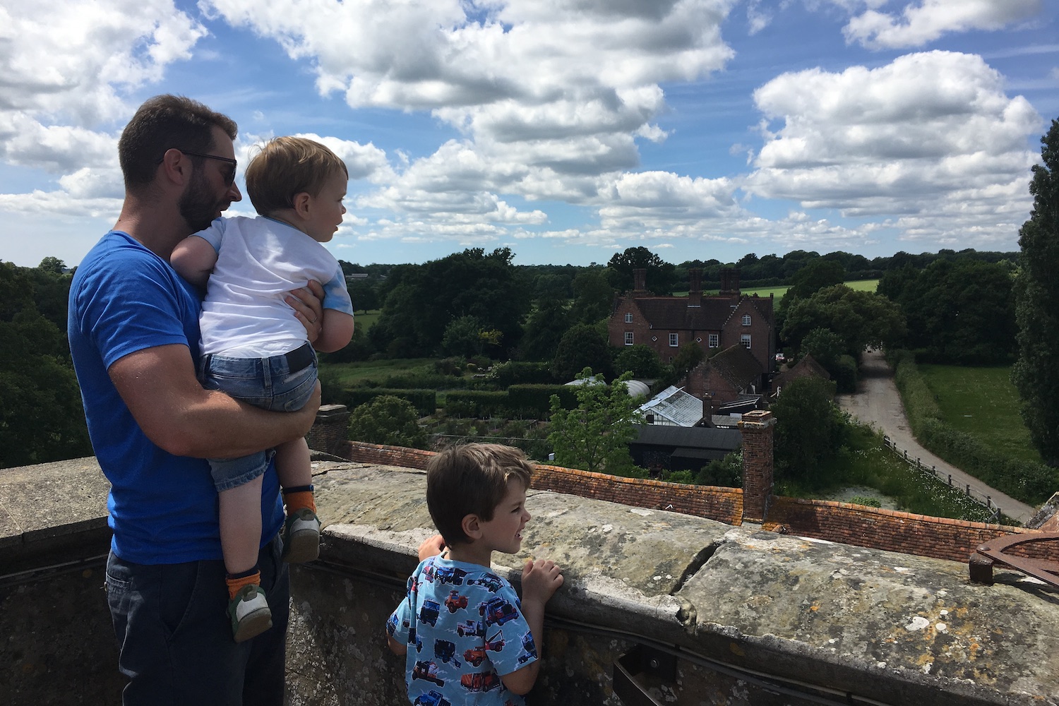 sissinghurst-castle-garden-1 Dad with his two sons standing on a viewpoint of Cranbrook Museum with a view of houses and rolling green fields in the background