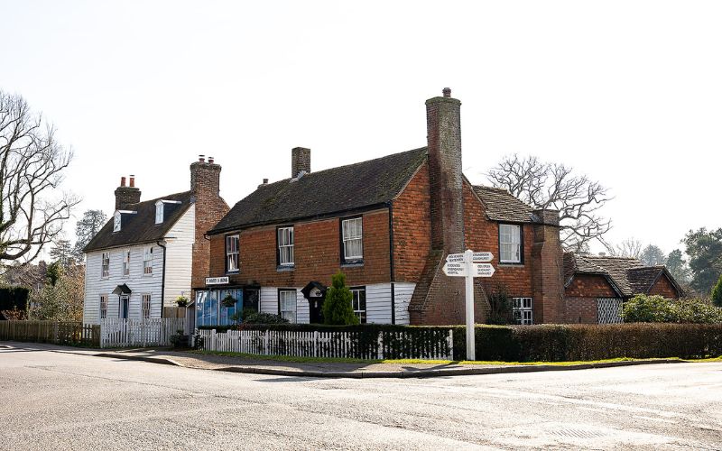 OId signpost in village with old house and shop behind
