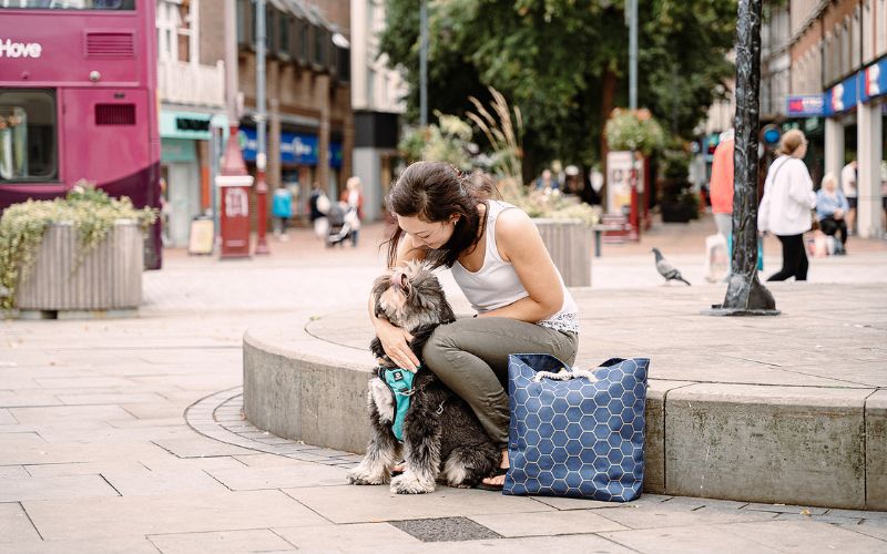 Woman sitting in town center petting dog